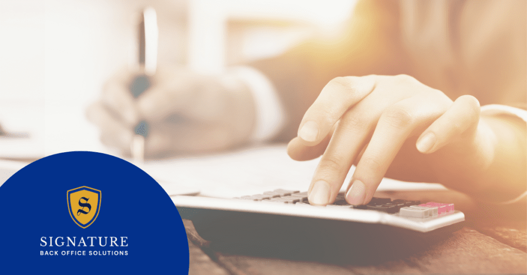 A person working on payroll while using a calculator.