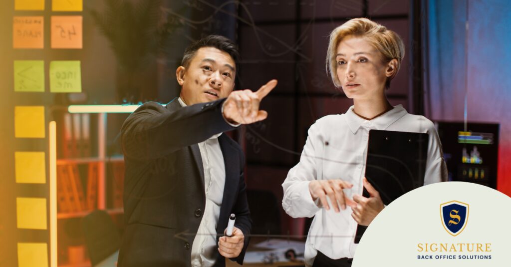 Two professionals in business attire discussing compliance management for staffing firms, pointing at a document or screen.