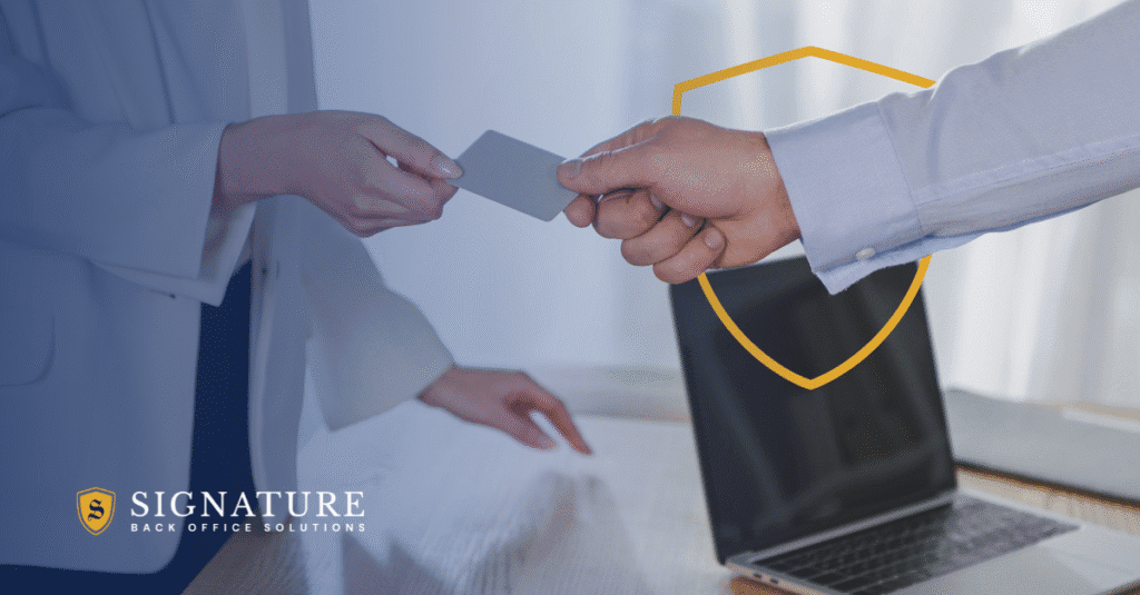 Two professionals exchanging a payment card in an office, representing the hidden costs of in-house payroll for staffing firms.