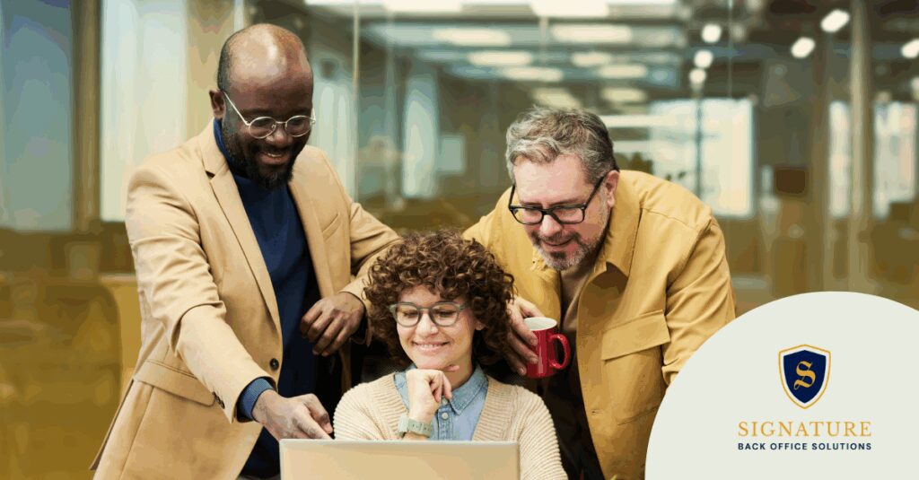 Three business professionals reviewing laptop discussing holiday staffing and payroll funding solutions.