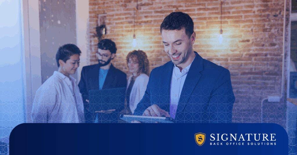 Smiling entrepreneur using tablet while team collaborates, showing staffing startup launch readiness.