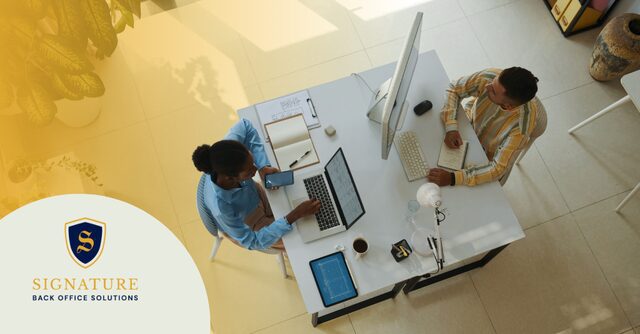 Two people at a shared desk work on multi-state staffing compliance.