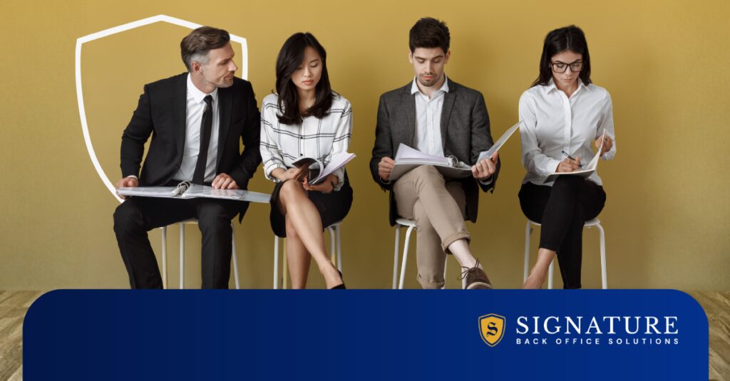 Four professionals reviewing documents in a waiting area, representing contract staffing growth without expanding internal headcount.