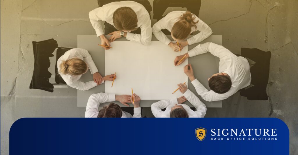 Overhead view of staffing professionals planning a contract staffing strategy at a conference table.